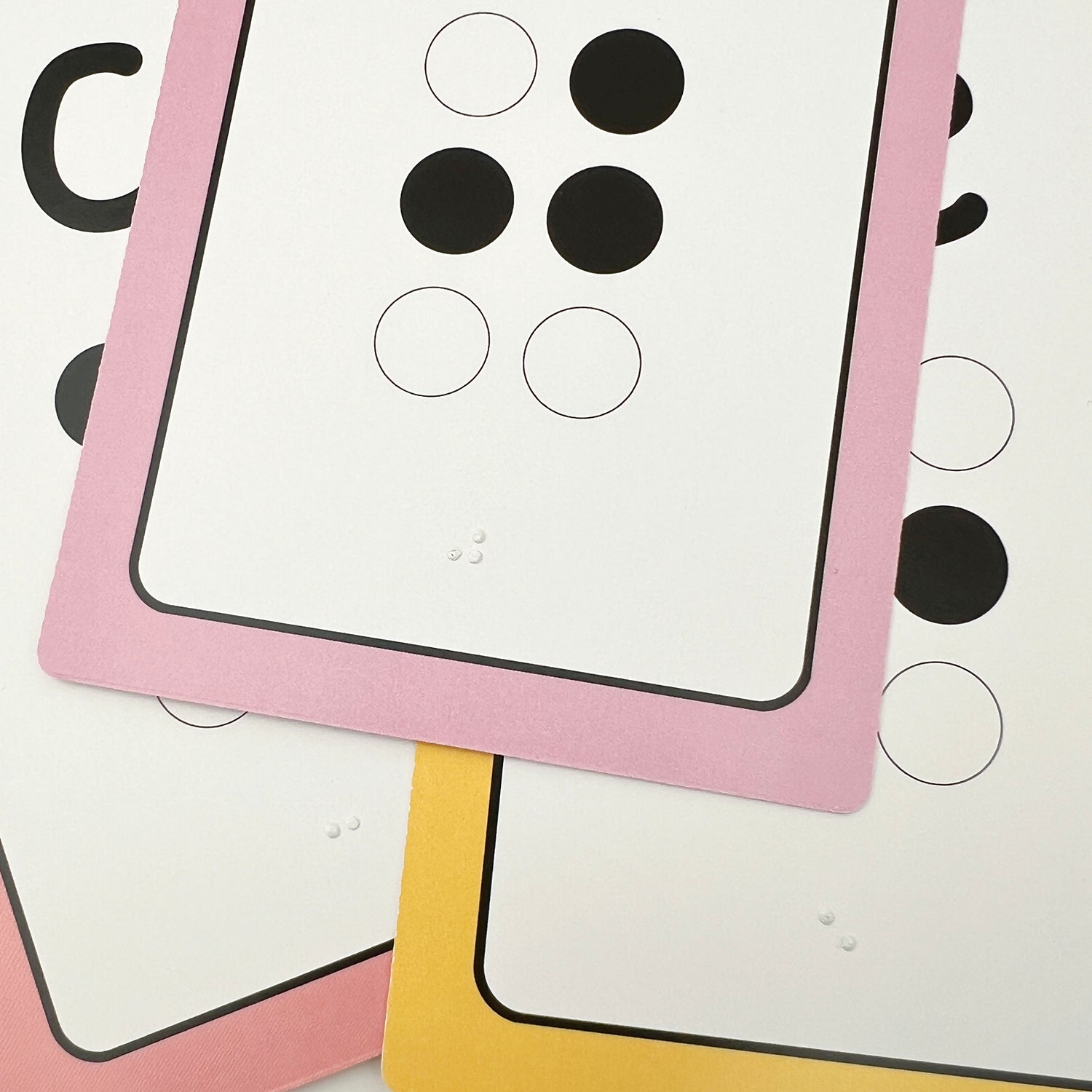 A close up of three flashcards showing the tactile braille dots.