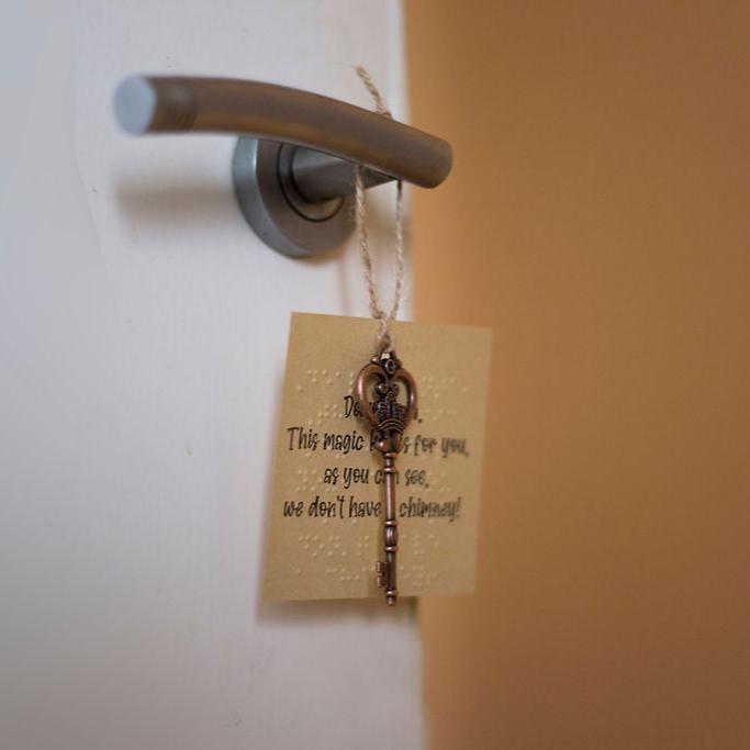 A decorative Santa key hanging on a door handle with a label which has print and braille. 