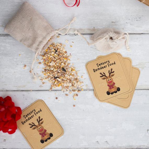 Labels saying sensory reindeer food in print and braille, with the image of a reindeer on the label. In the background is reindeer food and a hessian bag.