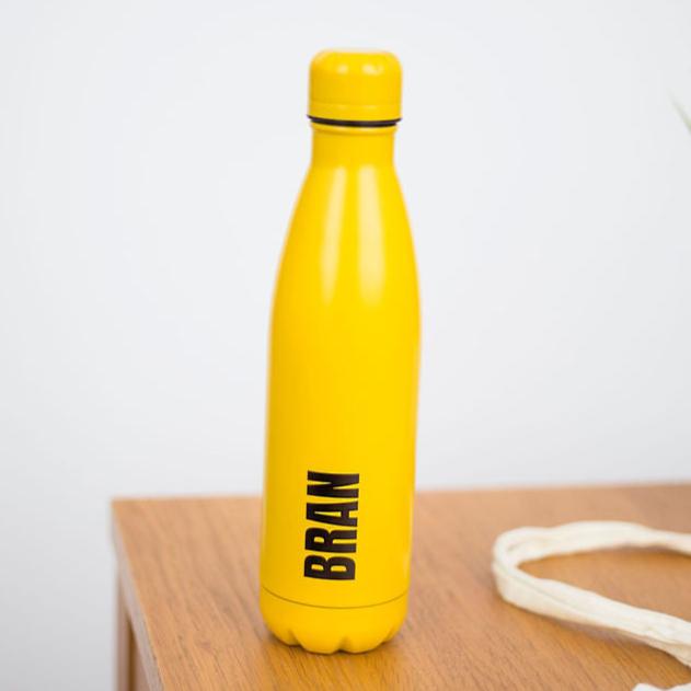 A yellow water bottle with BRAN written in big bold black text.