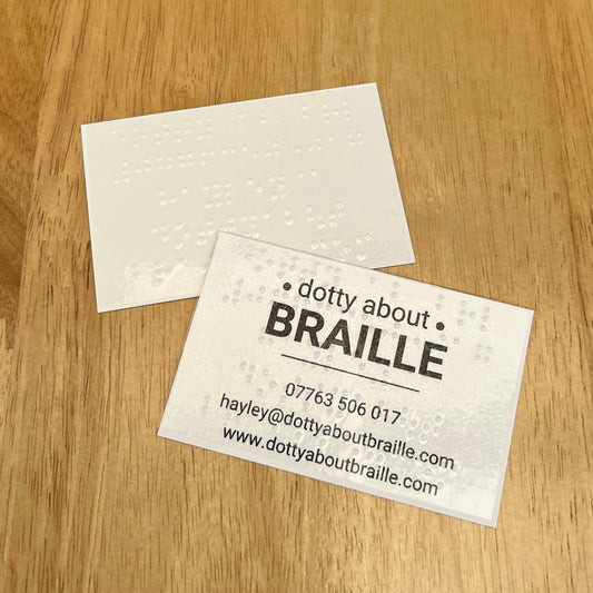 A dotty about braille business card that reads: dotty about braille, 07763506017, hayley@dottyaboutbraille.com, www.dottyaboutbraille.com with a braille sticker which has the business name, telephone number and email address on. There is another business card above which is blank apart from a braille label with the same information as the other label.