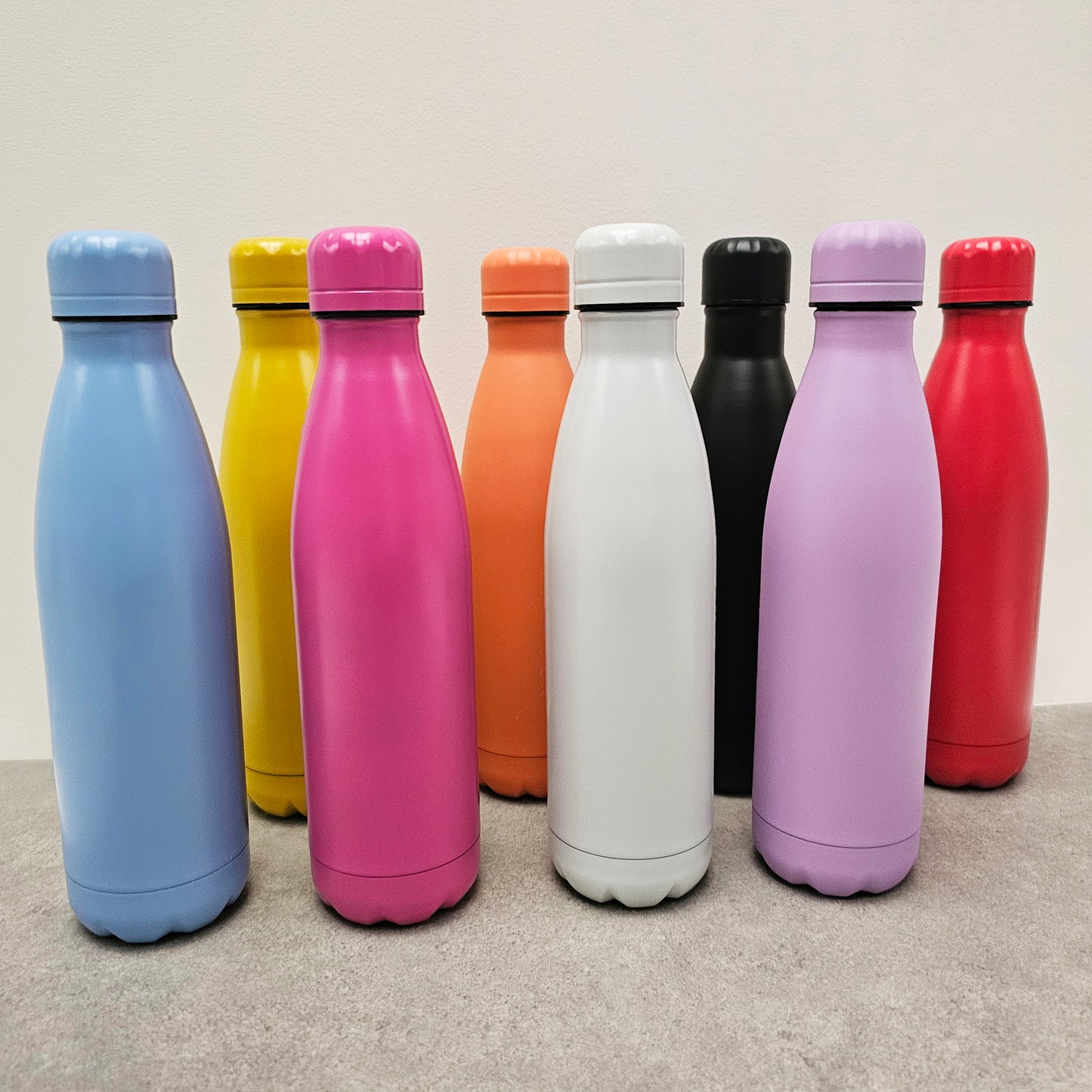 Coloured water bottles, blue, yellow, pink, orange, white, black, purple and red.